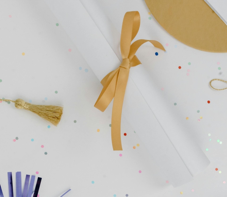 Stylish flat lay of graduation decorations with a diploma and confetti for celebrations.